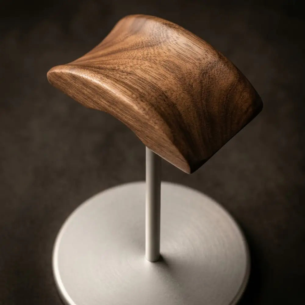 Close-up walnut and metal headphone holder displayed on a desk