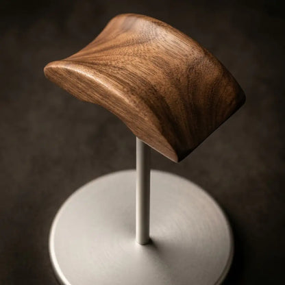 Close-up walnut and metal headphone holder displayed on a desk