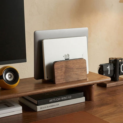 Walnut vertical laptop stand on desk setup with electronic devices and books on a wooden surface