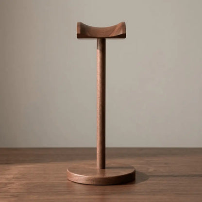 Minimal walnut headphone stand product shot on a dark desk surface