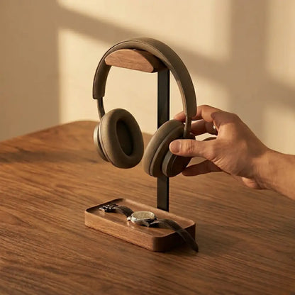 Hand placing headphones on a walnut headphone stand with tray