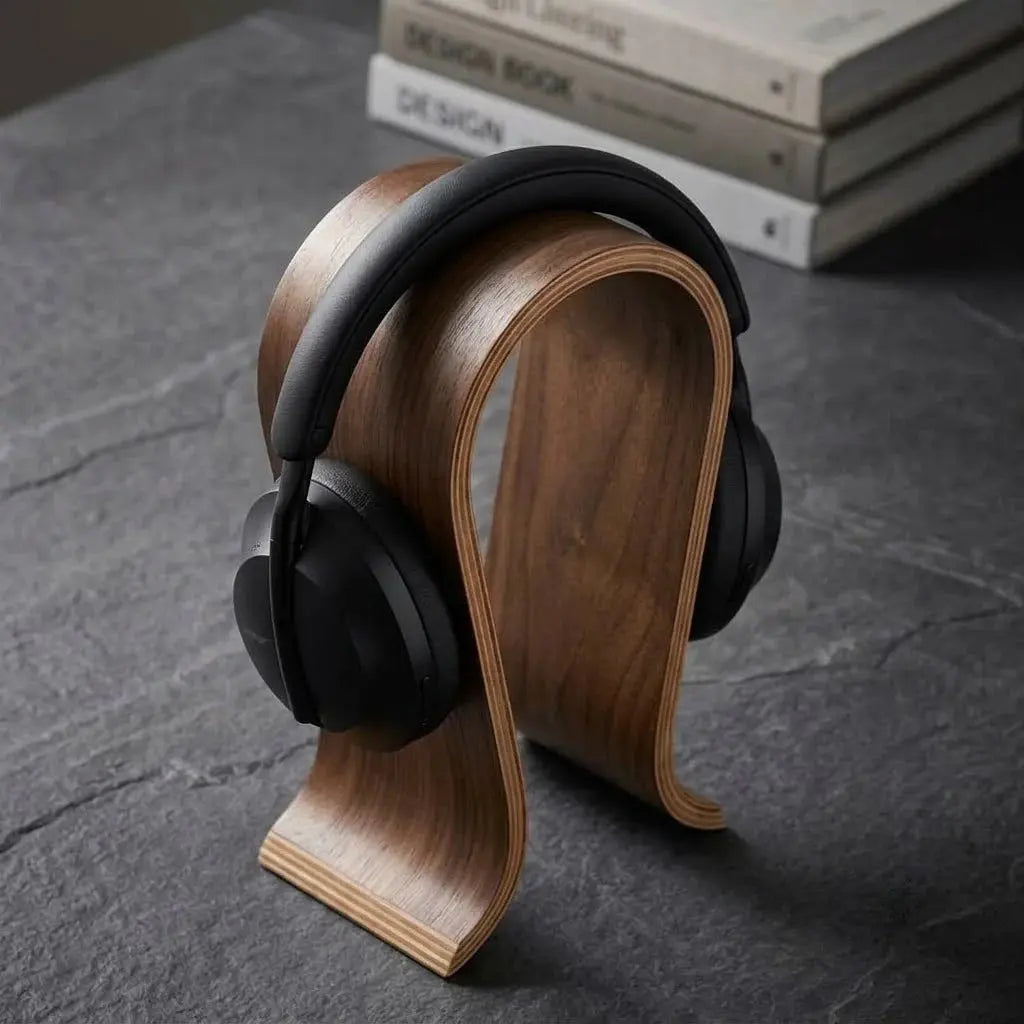 U-shaped wooden headphone stand holding black over-ear headphones.