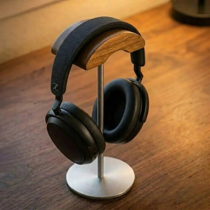 Walnut headphone stand with gray finish holding over-ear headphones on a wood desk