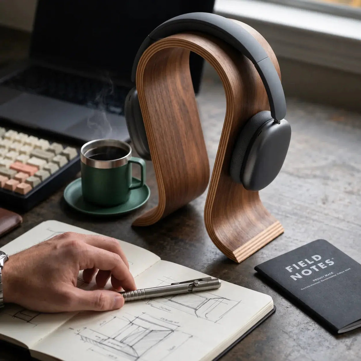 Wooden headphone stand beside a notebook and coffee during a daily desk routine.